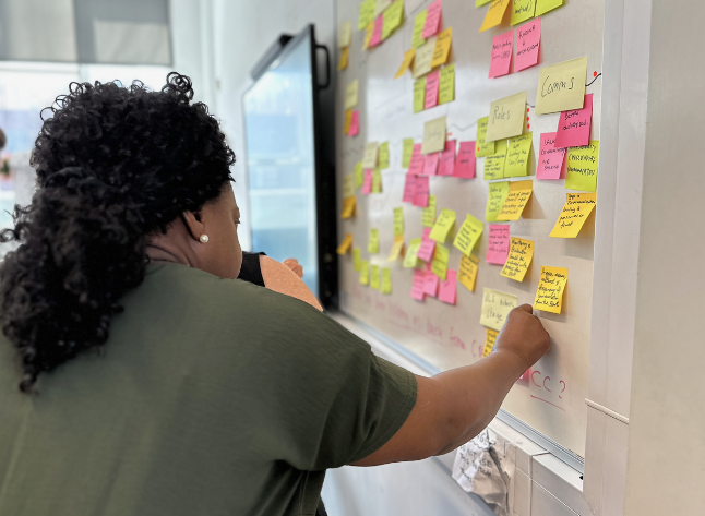 A black woman sticking post its up on a wall